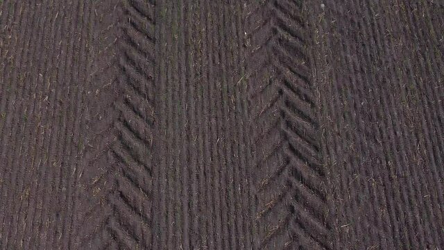 Tractor tyre tread print pattern aerial view in countryside fertile ploughed farmland field slow tracking down shot