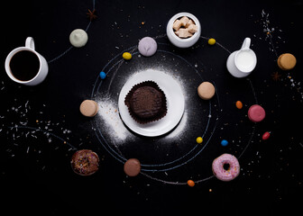 cup of coffee, donuts, macaroons, sugar, milk cream jug and cakes on the  black background look like coffee system