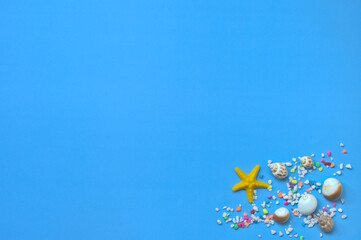 Fototapeta na wymiar Colorful pebbles, starfish, conches in the corner of the blue background, decorations, top view, copy space