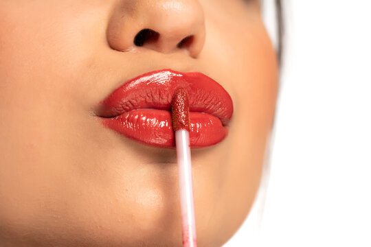 closeup of a young beautiful woman applies lip gloss
