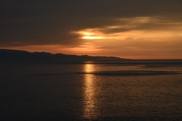 Golden sun rays making their way through the clouds, Golden reflection on the water 