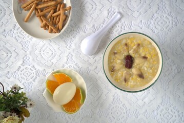 Healthy and nutritious lily red dates porridge, eggs, finger biscuits, oranges, spoon. Top view, white background