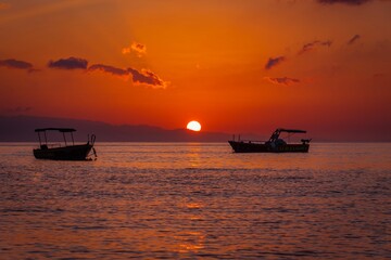 Sunrise over the horizon. Boats sailing in the sea