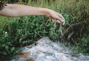 Young woman holding ashes near forest, ashes in hand close-up, tribal shaman near ashes. performing ancient ritual, wildfire concept, natural disaster concept