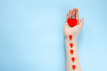 red heart in a child's hand on a blue background, charity and care, blood donation