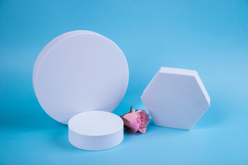 Premium paper podium on a blue paper background with an artificial rose flower.Layout for exhibitions, product presentations, therapy, relaxation and health