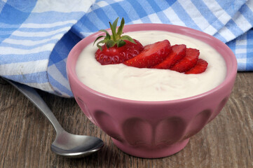 Ramequin de crème à la fraise maison avec une fraise fraîche coupée dessus en gros plan