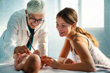 Pediatrician doctor medical examining little smiling baby, held by mother