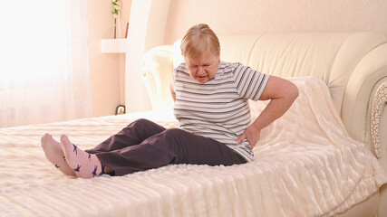 Elderly woman on bed with back pain