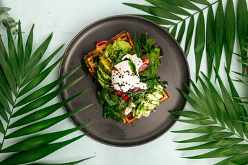 Top view on fresh waffle sandwich with avocado and poached egg
