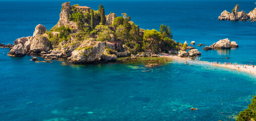 Crystal clear blue green waters surrounding the little island of Isola Bella in Taormina, Sicily. Panorama, copy space