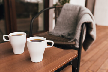 Two cups of coffee on the table on wooden brown terrace during evening sunset