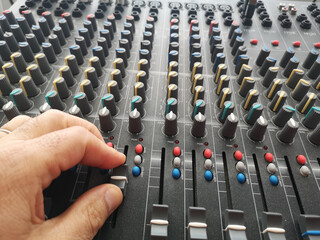 Selective focus shot of a male's hand adjusting an audio mixer