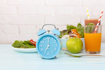 Selective focus of blue clock with Intermittent fasting diet food concept  and  fresh vegetables as part of a daily modern healthy lifestyle diet