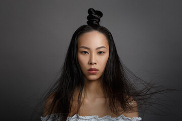 Portrait of a beautiful Asian girl with a puss hairstyle and hair fluttering in the wind isolated...