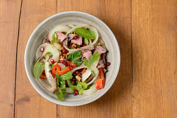 Salad with beef, onion and cilantro in sweet and sour sauce. With pomegranate seeds.