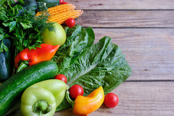 Assortment of fresh vegetables (peppers, cherry tomatoes, avocado, spinach, parsley, lettuce, corn) on a gray wooden background. Elements of vegan and keto diets. Healthy diet. Detox, 