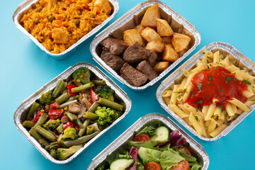 Take away healthy food in foil boxes on blue background
