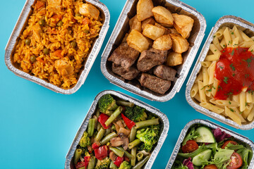Take away healthy food in foil boxes on blue background