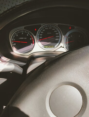 Sunlight and shadow on surface of steering wheel with car dashboard panel and indicator lights...