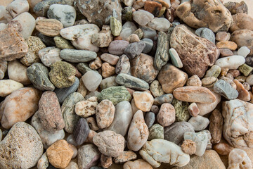 multicolored river pebbles stones randomly lie on the sand next to the sea. Macro photography. Close-up background concept, copy space