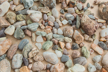 multicolored river pebbles stones randomly lie on the sand next to the sea. Macro photography. Close-up background concept, copy space