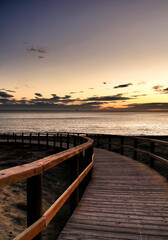 Fototapeta na wymiar Wooden walkway to the beach at sunrise in Alicante, Spain