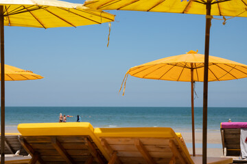 yellow beach umbrella with wooden bench as foreground. concept : travel sea in summer time.