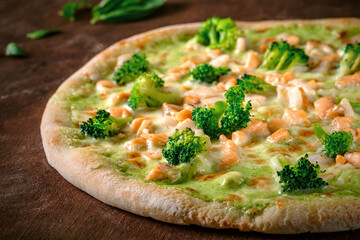 Pizza with broccoli, mozzarella and pesto sauce. Traditional Italian baked pizza on a wooden background. Close up