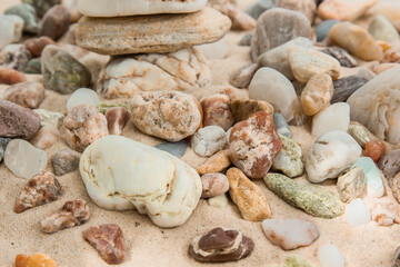 multicolored river pebbles stones randomly lie on the sand next to the sea. Macro photography. Close-up background concept, copy space