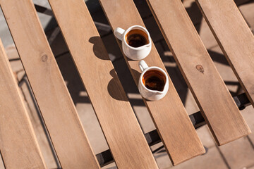 Cup of espresso coffee on wooden table of the summer veranda cafe. Closeup, top view, copyspace or place for text