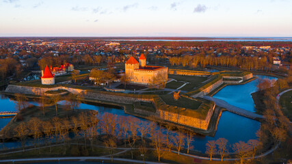 Aerial view to the sunset colored coastal historic medieval fortress with the surrounding water...