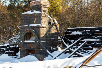 Ruins of a burnt house with a stone oven under the snow