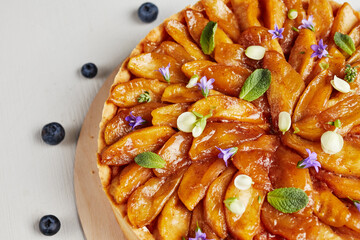 cheesecake with sliced fruits on a wooden base with dried flowers and blueberries