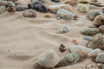 Fototapeta na wymiar multicolored river pebbles stones randomly lie on the sand next to the sea. Macro photography. Close-up background concept, copy space