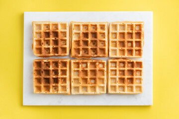 Belgian waffles on a yellow background Texture of different belgian waffles