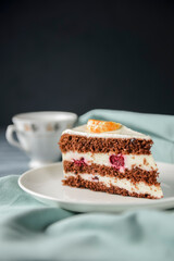 A piece of chocolate cake with vanilla cream. Berries inside and a piece of tangerine on top.