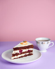 A piece of chocolate cake with vanilla cream. Berries inside and a piece of tangerine on top.