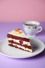 A piece of chocolate cake with vanilla cream. Berries inside and a piece of tangerine on top.