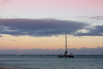 A boat sails into the sunset on Waikiki Beach, Hawaii