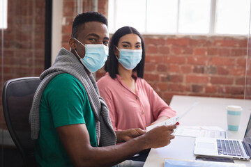 Portrait of diverse creative colleagues wearing face masks brainstorming in meeting room