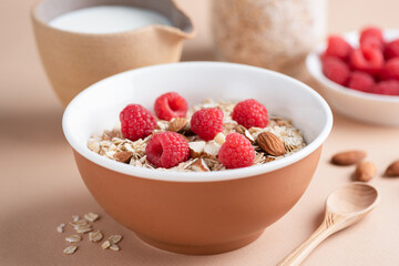 Muesli or granola with raspberries and chopped almonds in a bowl, healthy breakfast food for weight loss, dieting, clean eating menu