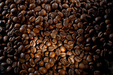 Coffee beans close up. Texture of brown coffee beans. Contrasting dramatic light as an artistic effect.