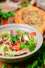 Salad with beef, onion and cilantro in sweet and sour sauce. With pomegranate seeds.