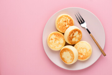 Cottage cheese fritters, Syrniki on a pink background, top view copy space for text or design elements