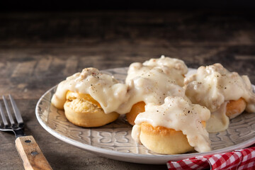 Traditional American biscuits and gravy for breakfast on wooden table