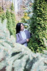 Portrait of young brunette woman in plaid coat in park enjoying the nature