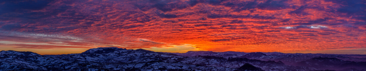 Fototapeta na wymiar Panorama spettacolare al tramonto, con cielo nuvoloso infuocato dal sole, visto dalla Repubblica di San Marino