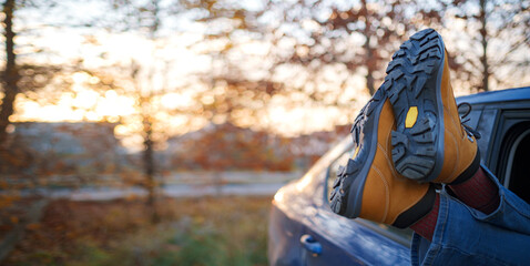 Woman feet on car door. Feet outside the window at sunset forest