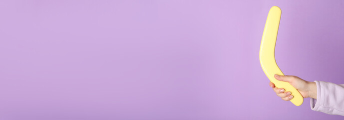 Woman holding boomerang on lilac background, closeup. Space for text - obrazy, fototapety, plakaty